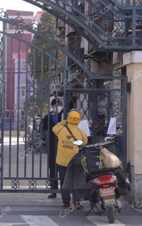 场景类：防疫期的物流，戴口罩的社区居民隔着栏杆收发快递