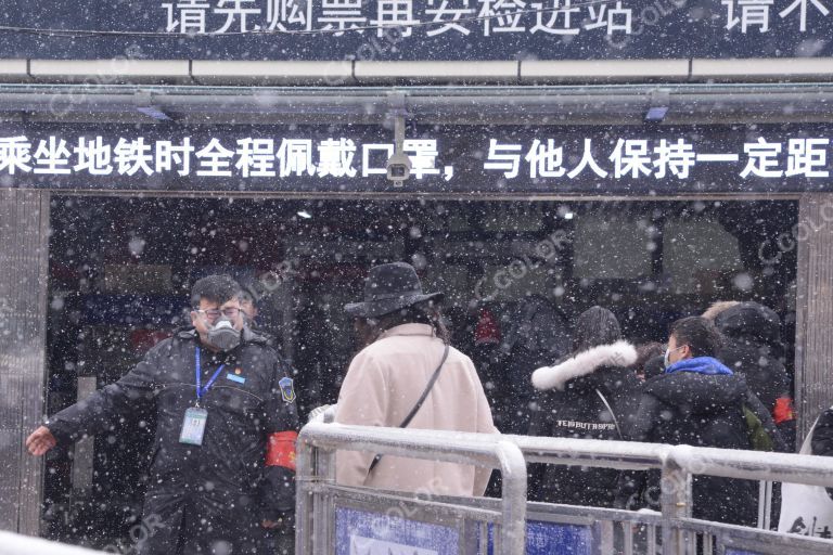 场景类：北京站地铁口，戴口罩的地铁员工在冒雪疏导返京客流有序进站