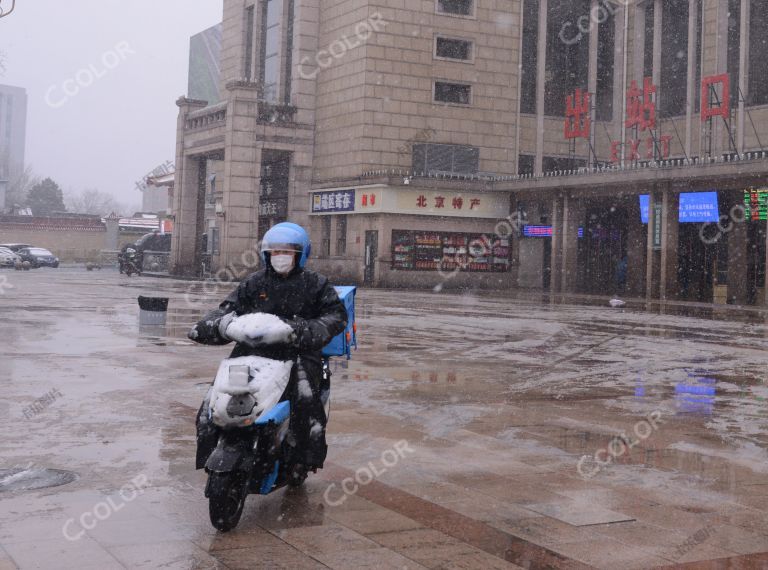 场景类：雪中北京站站前广场骑行的快递员
