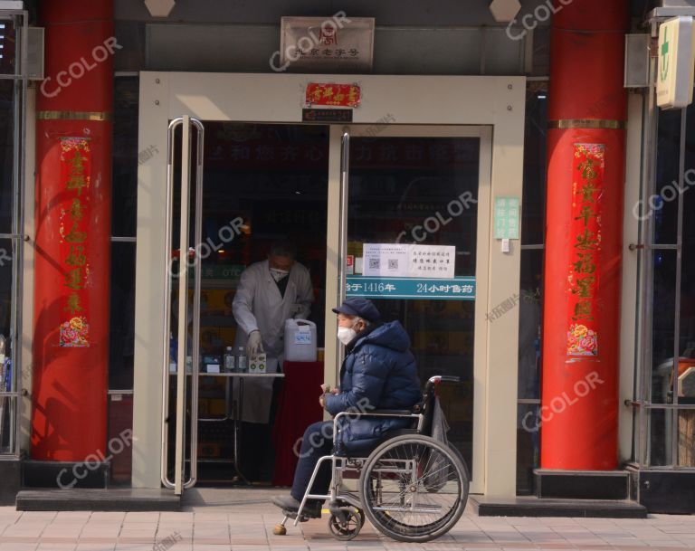 场景类：新冠防控期，戴口罩的老人坐在药店门前的轮椅上