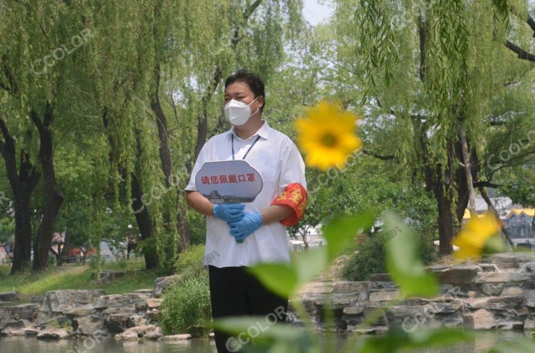 新冠疫情期的北京公园，安全员提示游客戴口罩