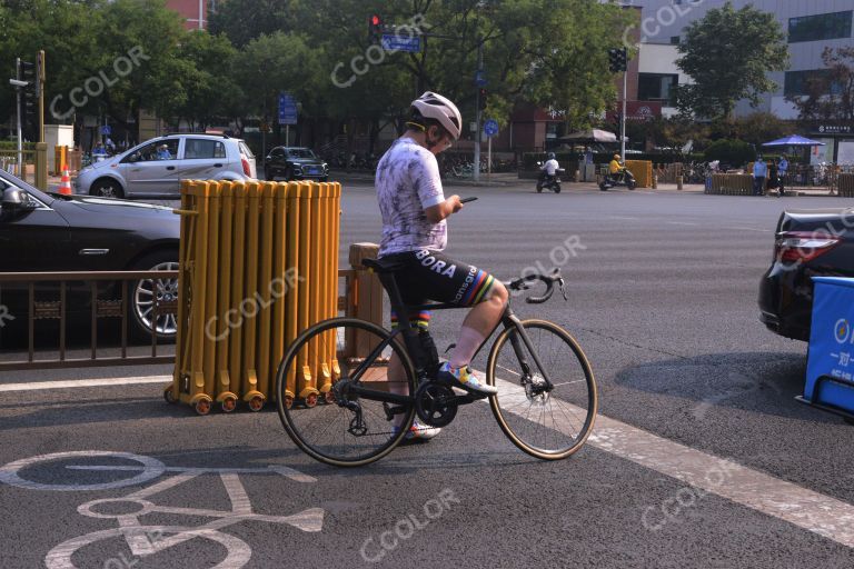 场景类：跨在自行车上看手机的青年